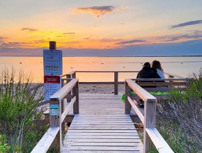 A couple sitting at the deck at Settler's Landing viewing the sunset